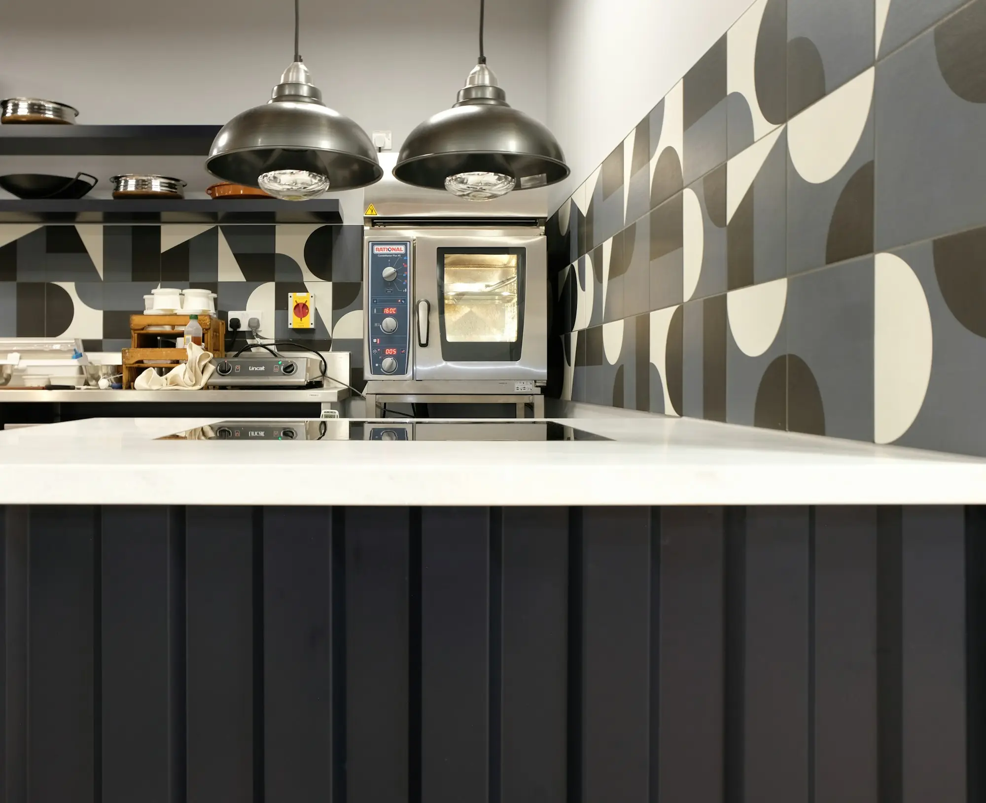 Commercial kitchen fit-out with patterned tiles and pendant lights