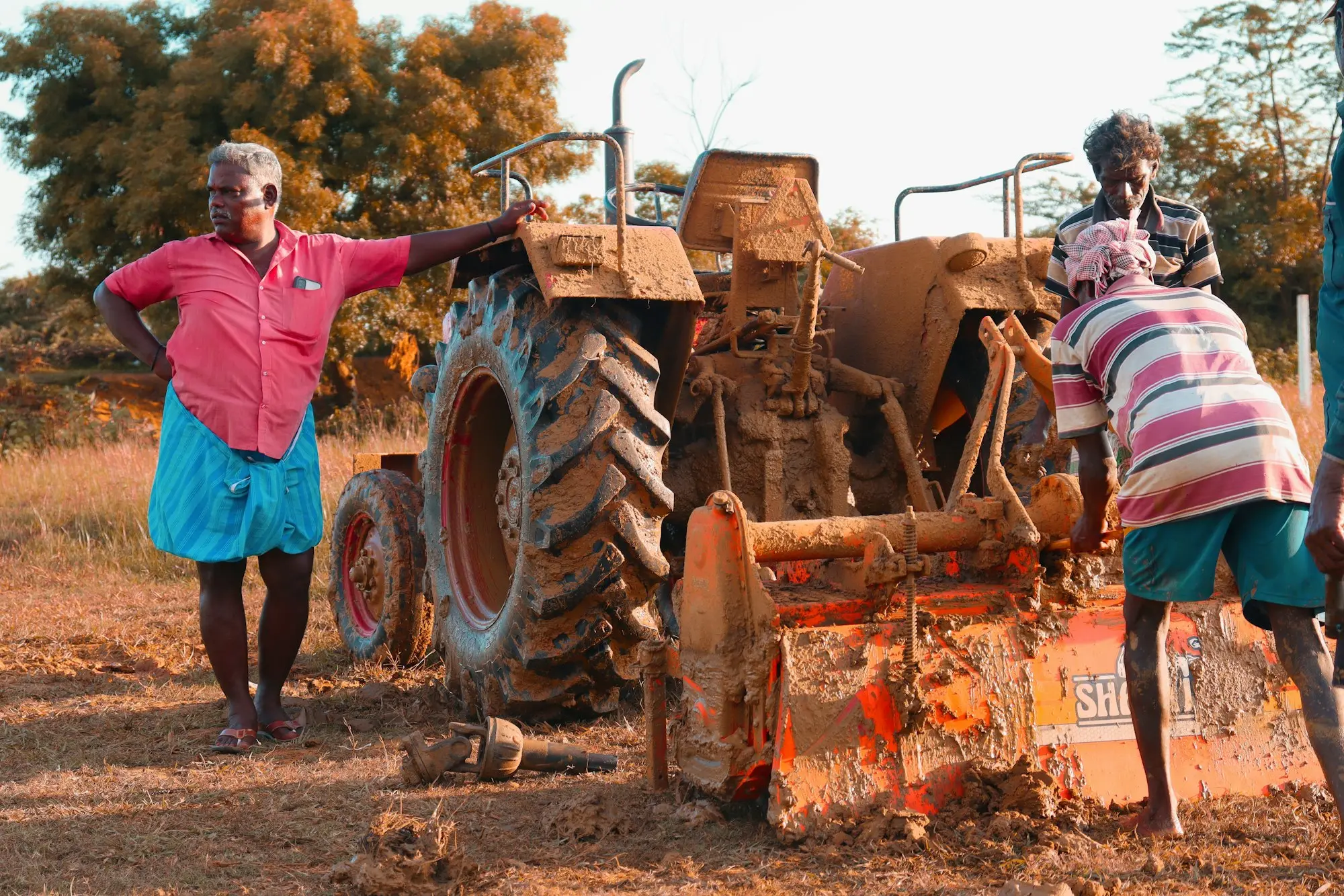 Two people standing next to a tractor