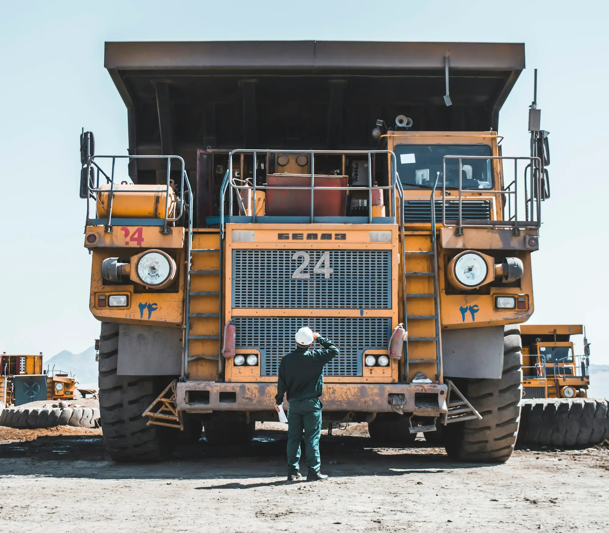 Worker standing beside a yellow mining truck