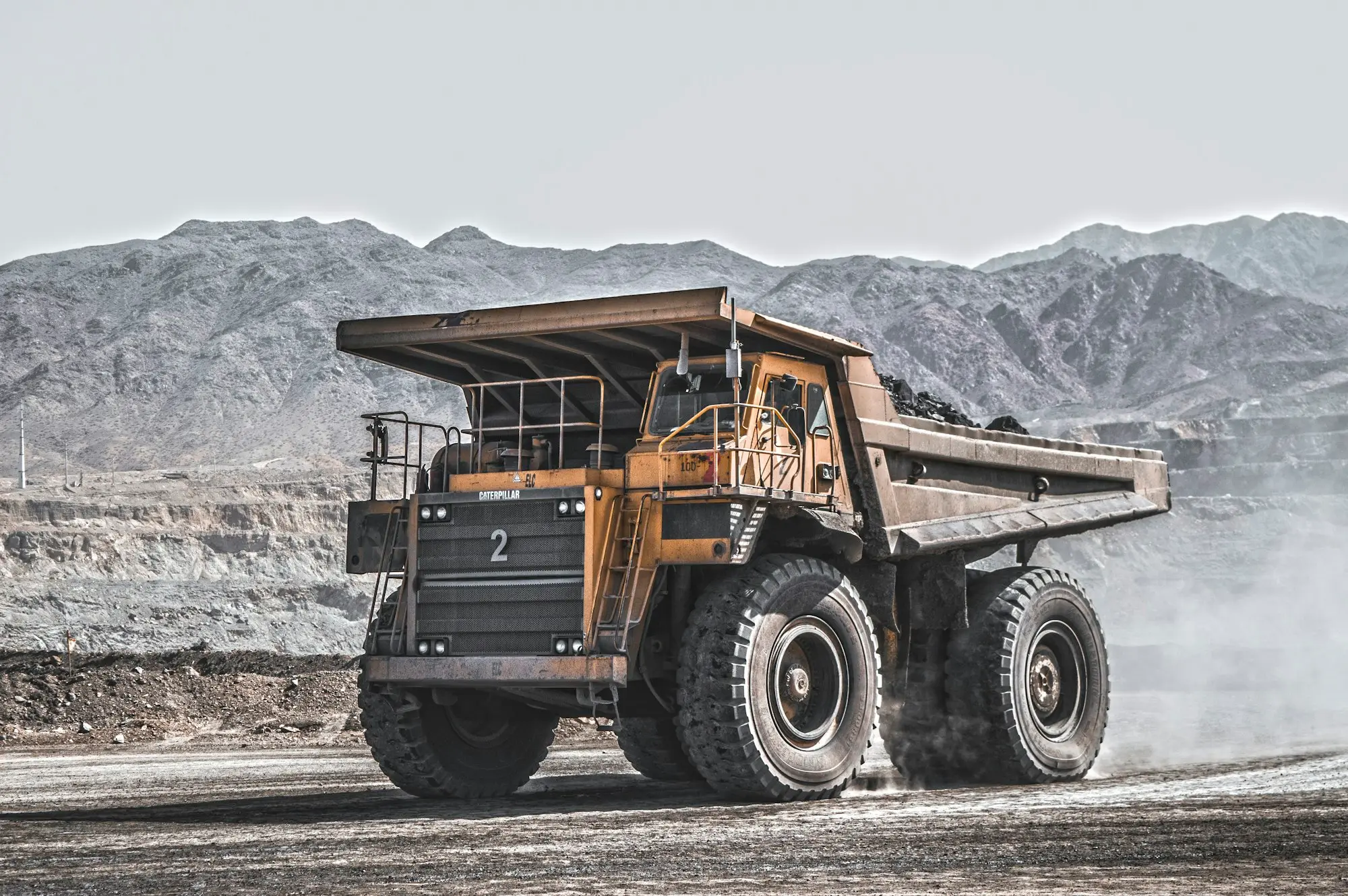 Yellow mining haul truck on a dusty road