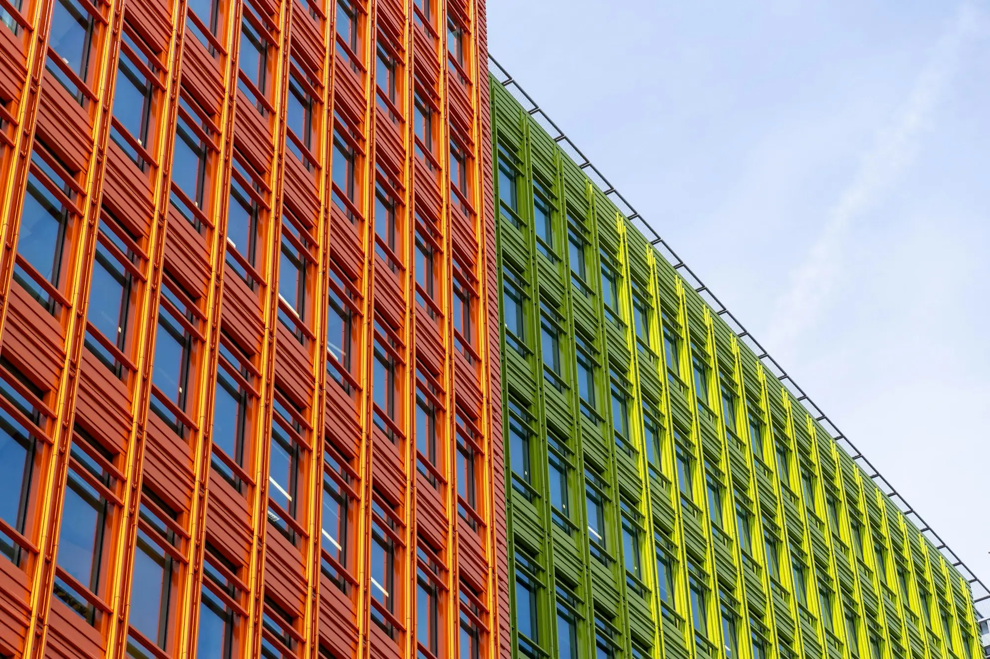 Modern commercial building with orange and green louvres against a blue sky