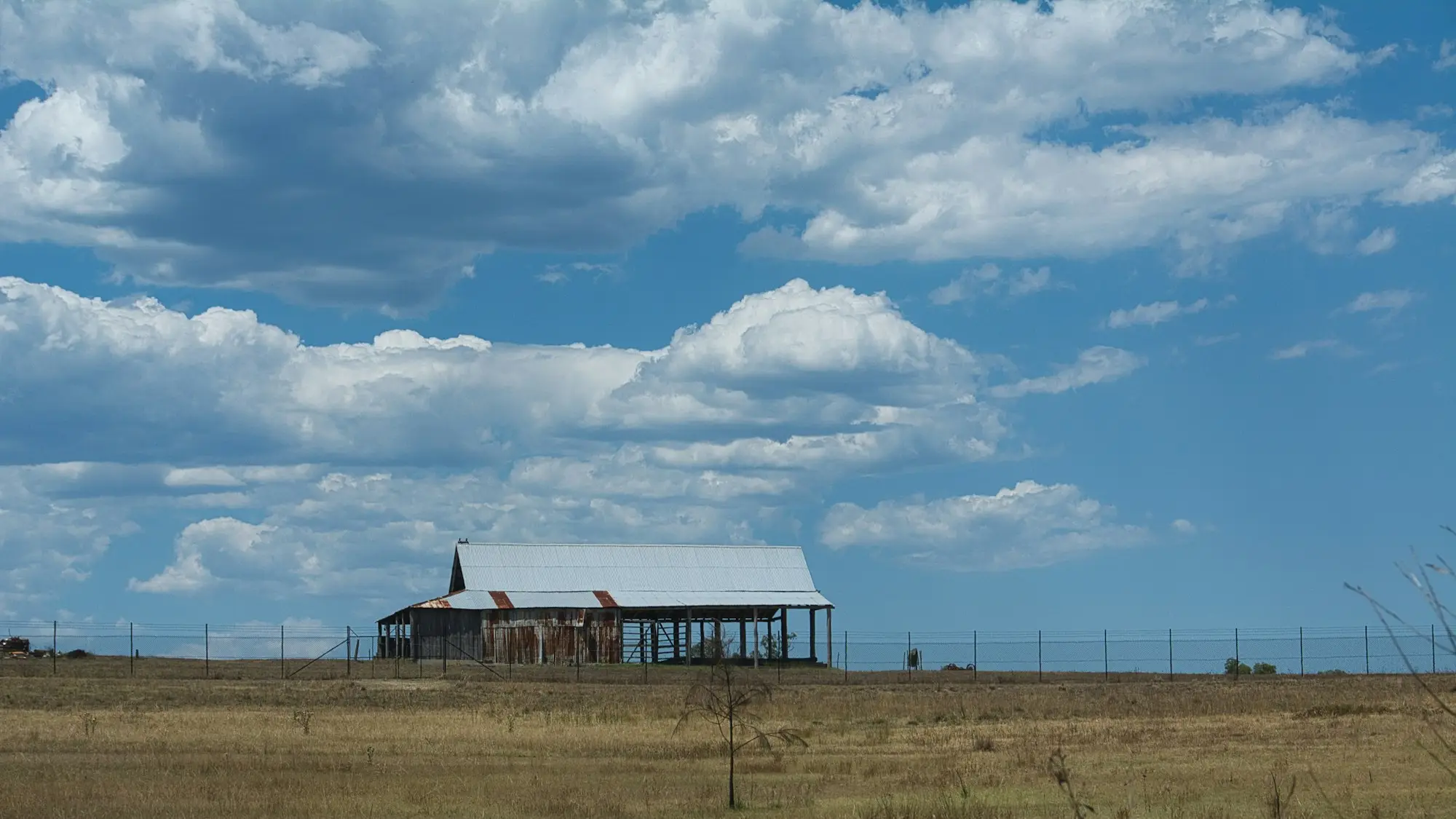 Old farm shed under a cloudy blue sky