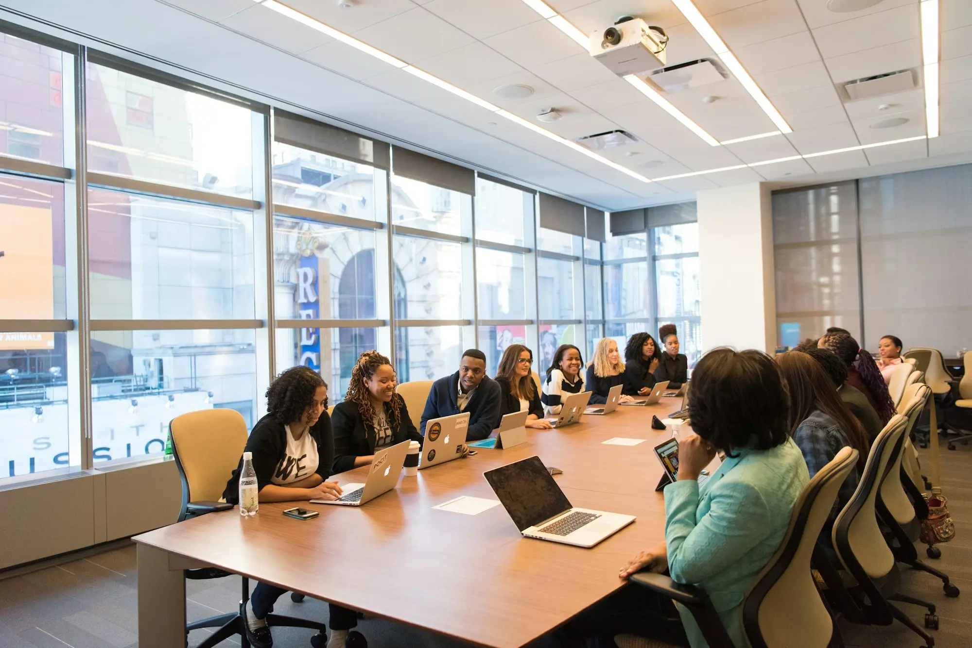 Team meeting around a wooden table with laptops