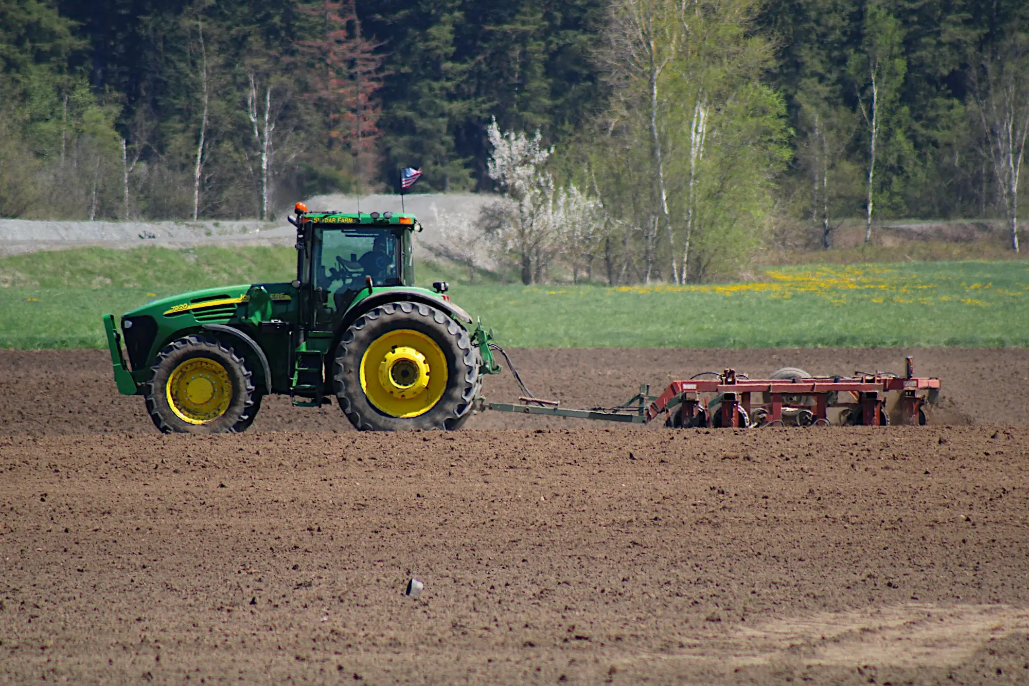 Tractor pulling a plough across a paddock