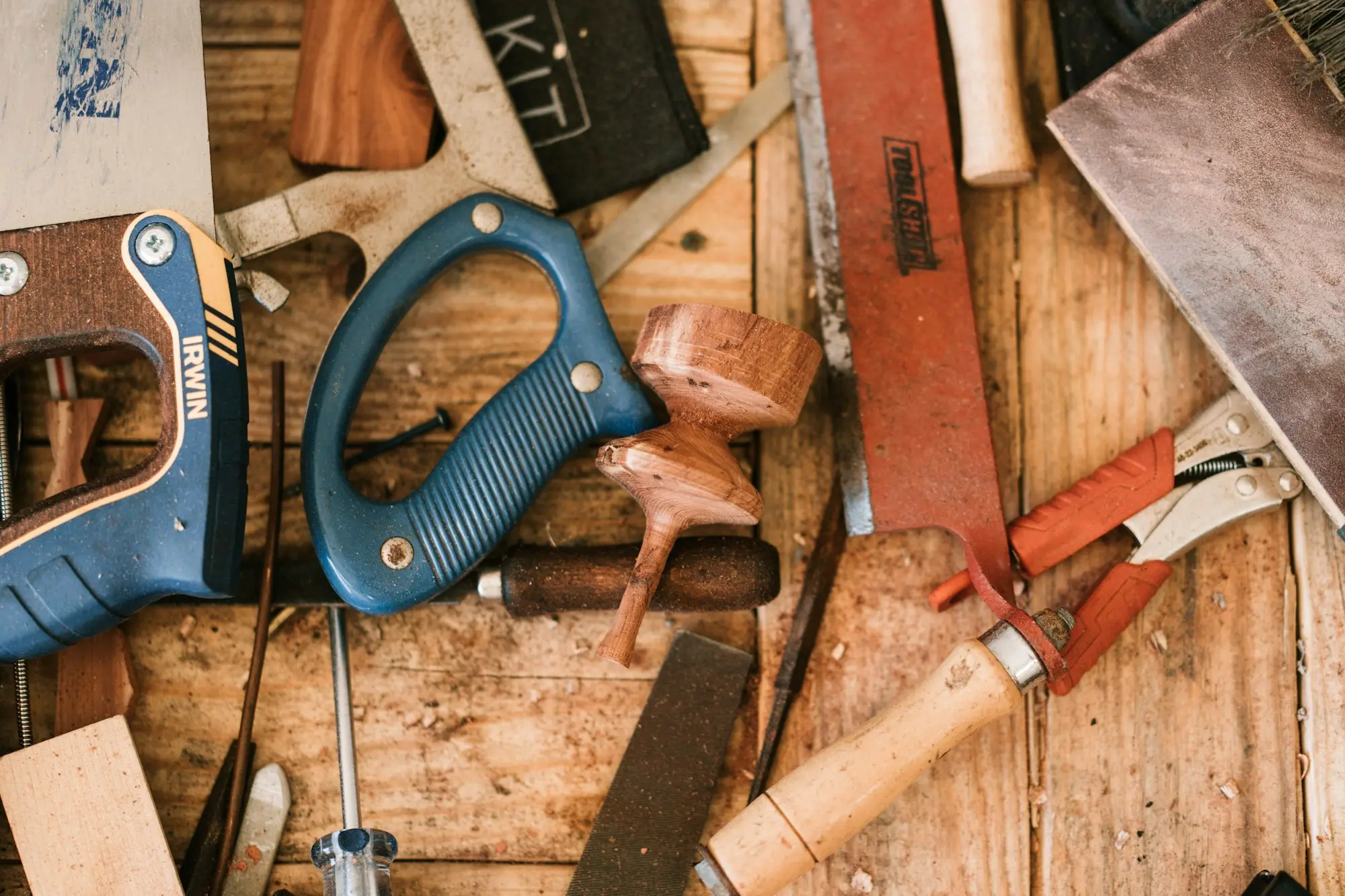 Pliers beside a timber-handled tool
