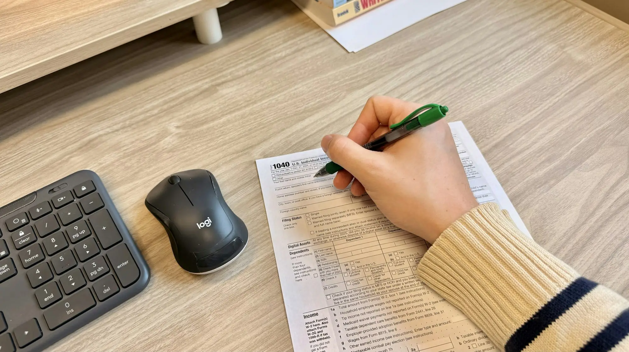 Hand writing on a document next to a keyboard